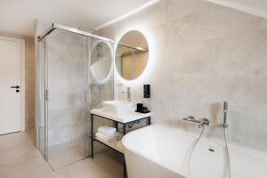 ein Badezimmer mit einer Badewanne, einem Waschbecken und einem Spiegel in der Unterkunft NOBILIS RESIDENCE in Prag