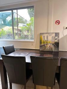 a dining room table with chairs and a painting on the wall at Sunshine Rooms in Maroochydore +4 photos