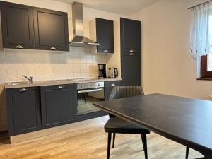 a kitchen with black cabinets and a table with chairs at Ferienwohnung am Borgwallsee in Steinhagen