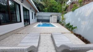 een patio met 2 banken en een zwembad bij Aonang Peace Pool Villa in Ban Khlong Haeng
