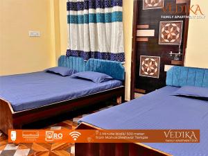 two twin beds in a room with a curtain at Vedika Yatri Grah - Entire Apartment in Ujjain