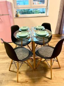 une table à manger avec quatre chaises et une table avec des assiettes vertes dans l'établissement Ferienwohnung Herbolzheim, à Herbolzheim