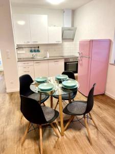 Il comprend une cuisine équipée d'une table, de chaises et d'un réfrigérateur rose. dans l'établissement Ferienwohnung Herbolzheim, à Herbolzheim