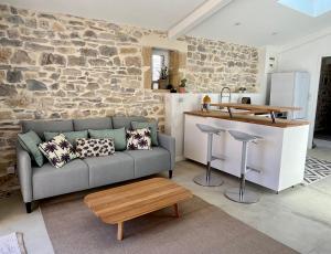 sala de estar con sofá y pared de piedra en Appartement cosy avec terrasse, en Saint-Gervasy