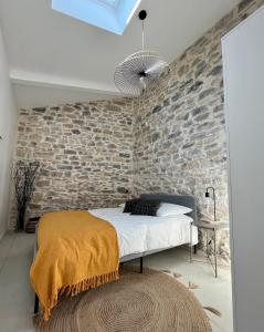 1 dormitorio con pared de ladrillo y 1 cama con alfombra en Appartement cosy avec terrasse, en Saint-Gervasy