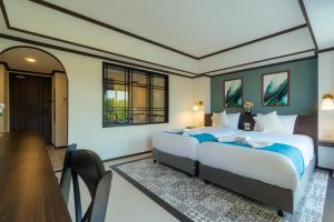 a bedroom with two beds and a table and chairs at Le ville lanna Chiang Mai Gate Old Town Hotel in Chiang Mai