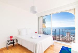 a bedroom with a white bed and a large window at Stunning Sea View 1 bedroom Near Monaco in Beausoleil