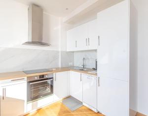 uma cozinha branca com pisos em madeira e armários brancos em Amazing Sea View T2- Near Monaco em Beausoleil