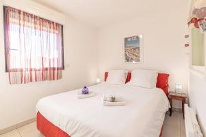 a white bedroom with a large white bed with two plates on it at Pretty T2 In Peace With Parking Menton in Menton