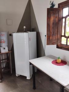 a kitchen with a white refrigerator and a table at Xareu-Balanço das Ondas! in Cabo de Santo Agostinho