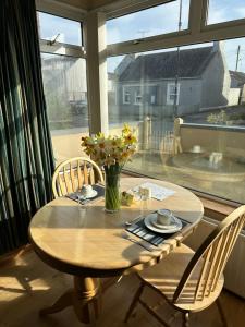 una mesa de madera con sillas y un jarrón de flores. en Marine Villa B&B en Annalong