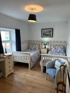 a bedroom with two beds and a chair at Marine Villa B&B in Annalong