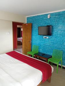 1 Schlafzimmer mit einem Bett und 2 Stühlen sowie einem TV in der Unterkunft Lovedale homestay in Udagamandalam