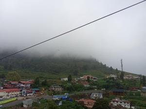 eine Stadt auf einem Hügel mit einem Nebel bedeckten Berg in der Unterkunft Lovedale homestay in Udagamandalam