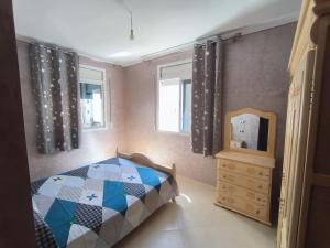 een slaapkamer met een bed, een dressoir en een spiegel bij Appartement Nador, Holi Flat in Nador