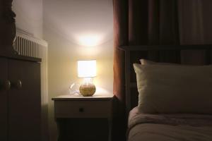 une lampe sur une table de nuit à côté d'un lit dans l'établissement Gaia Apartment, à Anatolí