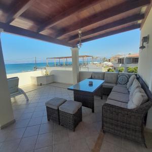 a patio with a couch and a table and the beach at Acharavi, villa next to the beach in Acharavi
