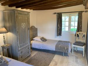 VimoutiersにあるGite le Normandのベッドルーム1室(ベッド1台、キャビネット、窓付)