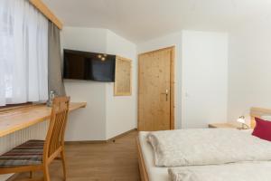 Dormitorio con cama, escritorio y TV en Winklhütte, en Forstau