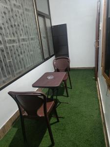 a table and chairs in a room with green carpet at Cozy Nest Homestay in Guwahati