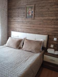 a bedroom with a bed with a wooden wall at Mountain Breeze in Qırızdǝhnǝ