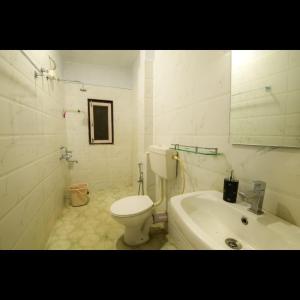 a white bathroom with a toilet and a sink at Cozy Nest Homestay in Guwahati