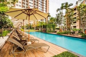 a swimming pool with chairs and an umbrella at unixx city ​​center high floor amazing sea view24f in Pattaya South