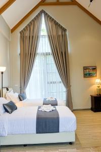 two beds in a bedroom with a large window at Phuping Valley Resort in Tak