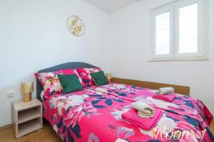 a bedroom with a bed with a pink floral bedspread at Diamond Sea - Vacation House with Private Parking and a Big Terrace over the Sea in Dubrovnik