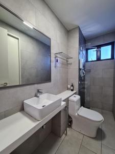 ein Badezimmer mit einem Waschbecken, einem WC und einem Spiegel in der Unterkunft The Shore - JJ's Unit with City View in Kota Kinabalu
