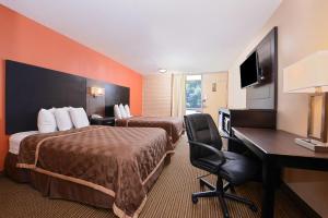 a hotel room with two beds and a desk at Americas Best Value Inn - Collinsville / St. Louis in Collinsville