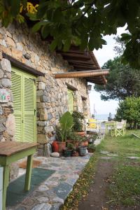 ein Steinhaus mit grünen Türen und einer Bank in der Unterkunft Country House Spitaki Λόχος in Velika