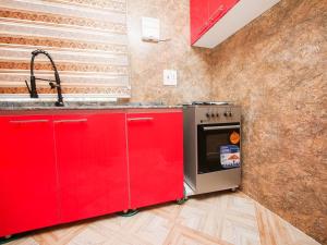 een keuken met rode kasten en een fornuis bij DULCE HOMES 2 BEDROOM FURNISHED SHORT LET in Abeokuta