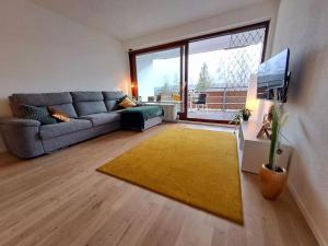 a living room with a couch and a large window at Schwarzwald-Traum mit Pool und Sauna in Unterkirnach