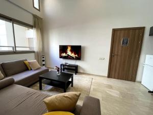 sala de estar con sofá y mesa con chimenea en Luxury apartment 5 minutes Casablanca Airport en Nouaceur