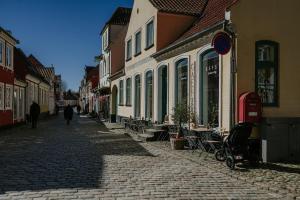 a person walking down a cobblestone street with buildings at KEFS Guesthouse & Café in Ærøskøbing