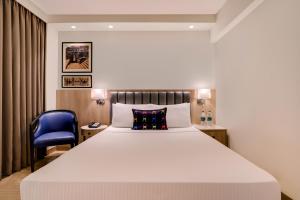 a bedroom with a large bed and a blue chair at Keys Select by Lemon Tree Hotels, Pimpri, Pune in Pune