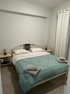 Mimozas Apartment Porto Heli في بورتوخيلي: غرفة نوم عليها سرير وفوط