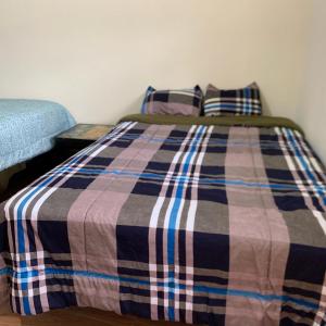 1 cama con manta a cuadros y 2 almohadas en Casa Campo Juive Grande en Riobamba