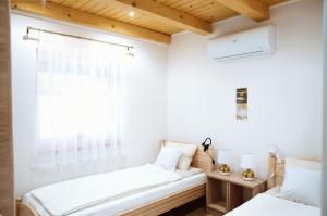 Dos camas en una habitación con ventana. en Vízitündér Pihenőpark Apartmanok, en Újhartyán