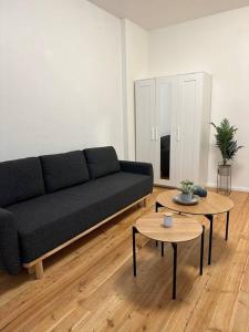 a living room with a black couch and two tables at Modern 2Room Apartment/Neukölln in Berlin