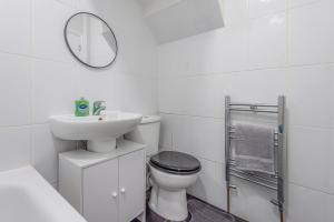 uma casa de banho com um WC, um lavatório e um espelho. em Modern family home w/Wi-Fi, Netflix, self check-in em Londres
