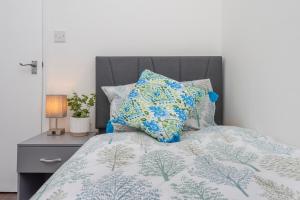 ein Bett mit einer blauen und weißen Bettdecke und Kissen in der Unterkunft Modern family home w/Wi-Fi, Netflix, self check-in in London