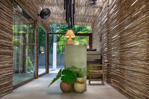 a hallway with a table and a lamp and plants at Pousada Seis e Meia in Trancoso