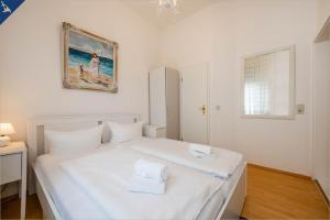 ein weißes Bett in einem Zimmer mit einem Gemälde an der Wand in der Unterkunft Villa Seeland Villa Seeland App 5 in Heringsdorf
