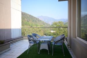 a table and chairs on a balcony with a view at The Ganges View Luxury Penthouse by iTvara in Rishīkesh