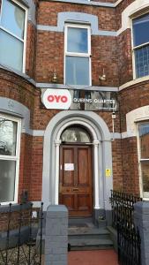 une porte d'entrée d'un bâtiment en briques avec un panneau wvu sur celui-ci dans l'établissement OYO Queens Quarter, à Belfast