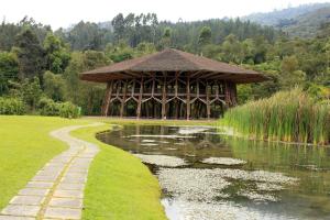 ein großes Holzgebäude neben einem Teich und einem Fluss in der Unterkunft Estelar Recinto Del Pensamiento Hotel Y Centro De Convenciones in Manizales