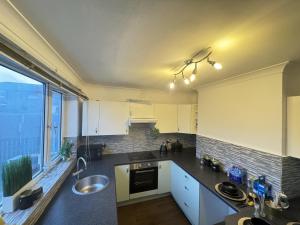 uma cozinha com armários brancos e uma grande janela em Okapi peace of paradise em Leeds