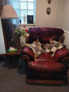 a living room with a leather chair with pillows at Cheerful 3-bedroom townhouse with free parking on site in Taunton